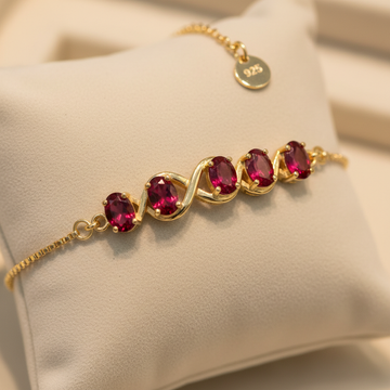 925 gold-plated silver July birthstone charm bracelet with oval ruby CZ stones on cream background