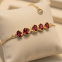 925 gold-plated silver July birthstone charm bracelet with oval ruby CZ stones on cream background
