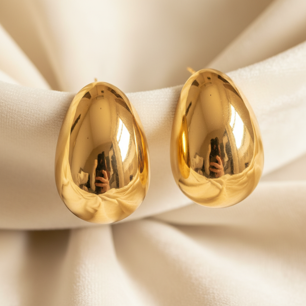 Oversized chunky gold dome teardrop drop earrings on cream background