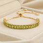 14K gold plated August birthstone baguette bracelet with peridot CZ stones on cream background