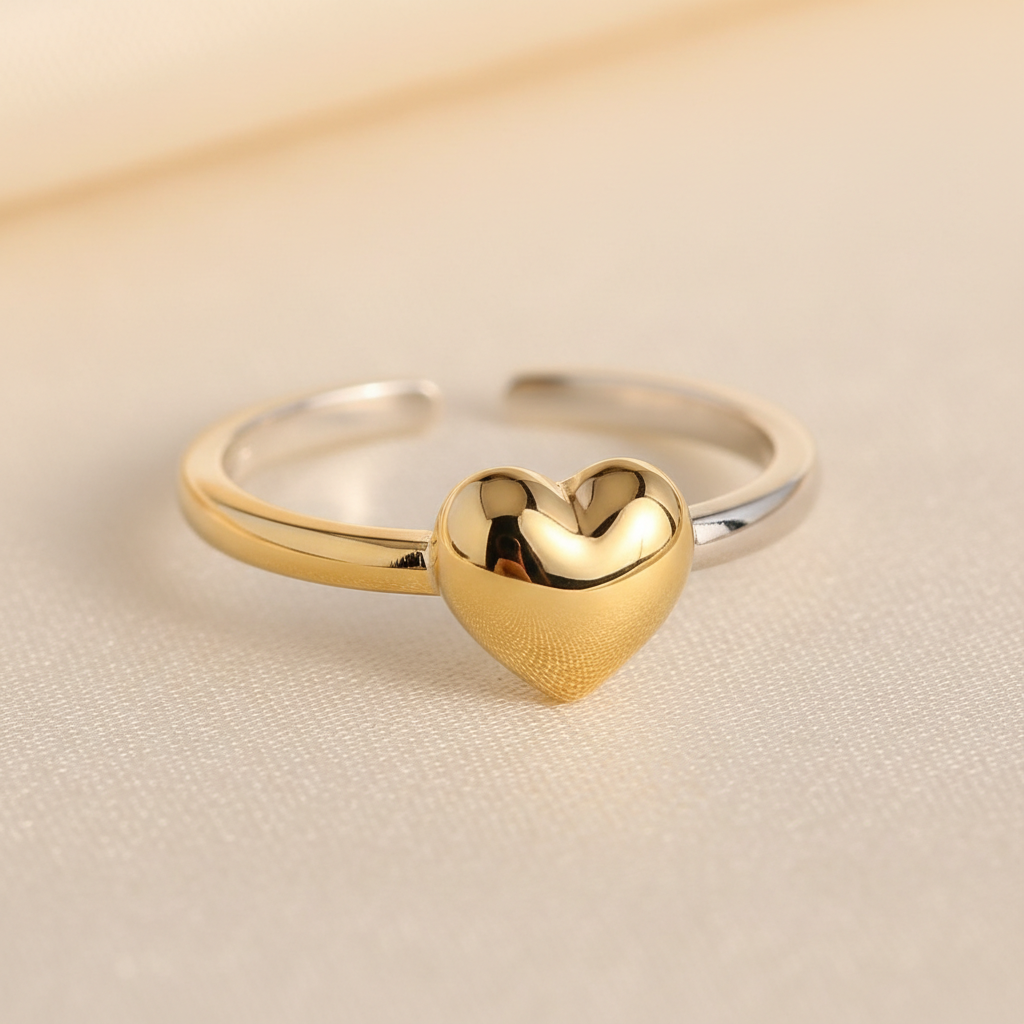 Heart charm ring in gold and silver electroplated alloy on a cream background