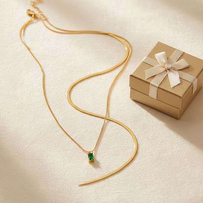 Flat lay of 14K gold birthstone layered necklace set with gift box on cream surface