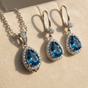 925 sterling silver London blue topaz teardrop halo necklace and earrings set on cream background